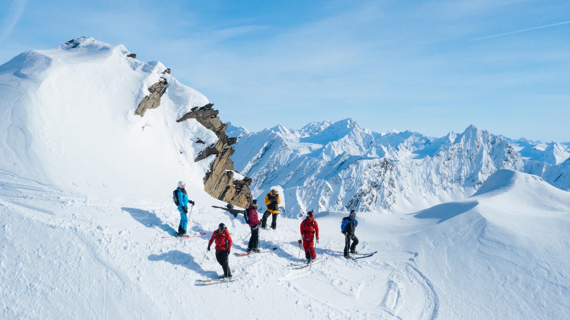 Group of skiers on a pristine mountain summit in the Chugach Mountains during a luxury Alaska heli skiing experience with Valdez Heli-Ski Guides near Valdez, Alaska